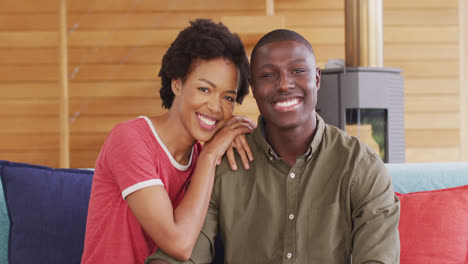 Video-of-happy-african-american-couple-sitting-on-sofa-and-looking-at-camera