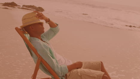 African-american-man-sitting-on-the-chair-and-relaxing-at-the-beach