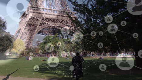 Animation-Von-Profilen,-Die-Durch-Linien-über-Einem-Mann-Verbunden-Sind,-Der-Am-Telefon-Vor-Dem-Eiffelturm-Im-Park-Spricht