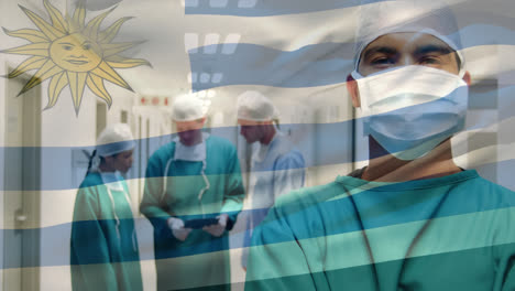 Animation-of-waving-uruguay-flag-over-portrait-of-biracial-male-surgeon-in-surgical-mask-at-hospital