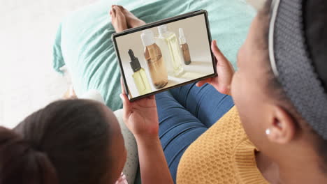 African-american-mother-and-daughter-using-tablet,-online-shopping-for-beauty-products,-slow-motion