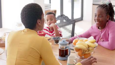 Madre-Afroamericana-Con-Hijo-E-Hija-Desayunando-En-La-Mesa-De-La-Cocina,-Cámara-Lenta