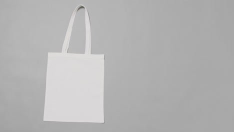 Close-up-of-white-bag-on-grey-background,-with-copy-space,-slow-motion