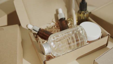 Nahaufnahme-Von-Kartons-Mit-Glasflaschen,-Cremewanne-Und-Zahnbürste-Auf-Beigem-Hintergrund