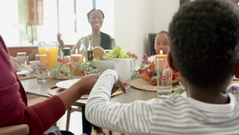 Happy-african-american-multi-generation-family-holding-hands-at-thanksgiving-dinner,-slow-motion