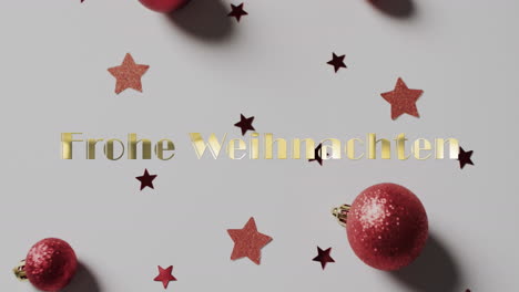 Frohe-Weihnachten-Text-In-Gold-Mit-Roten-Weihnachtskugeln-Und-Sternen-Auf-Weißem-Hintergrund