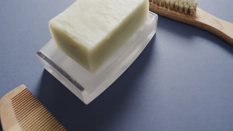 Close-up-of-soap,-brush-and-comb-on-blue-background