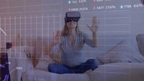 Animation-of-stock-market-data-processing-over-caucasian-woman-wearing-vr-headset-at-home