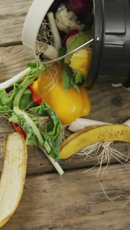 Video-of-white-compost-bin-with-organic-waste-lying-on-grey-wooden-background