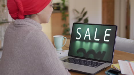 Biracial-woman-using-laptop,-online-shopping-during-sale,-slow-motion