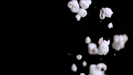 Animation-of-close-of-popcorn-falling-against-copy-space-on-black-background