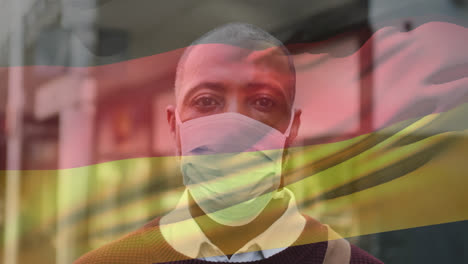 Animation-of-waving-germany-flag-over-portrait-of-african-american-man-wearing-face-mask-on-street