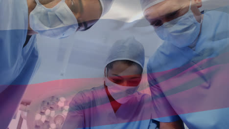Animation-of-waving-russia-flag-against-team-of-diverse-surgeons-performing-operation-at-hospital