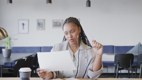 Serious-african-american-casual-businesswoman-looking-at-documents-during-video-call,-slow-motion