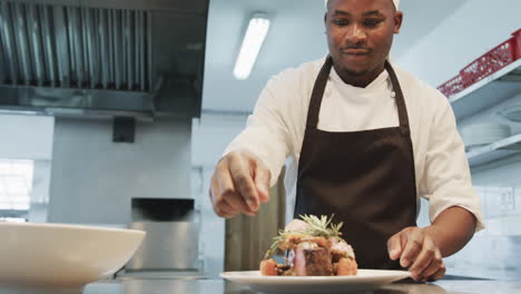African-american-male-chef-decorating-meal-in-kitchen,-slow-motion