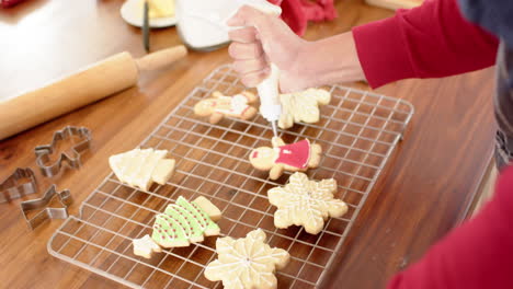 Biracial-man-decorating-christmas-cookies-in-kitchen-at-home,-slow-motion