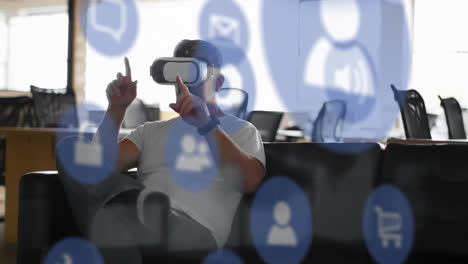Animation-of-computer-application-icons-over-caucasian-man-using-vr-headset-and-gesturing-in-office