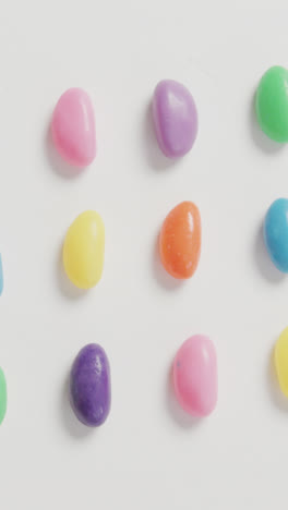 Video-of-overhead-view-of-rows-of-multi-coloured-sweets-over-white-background