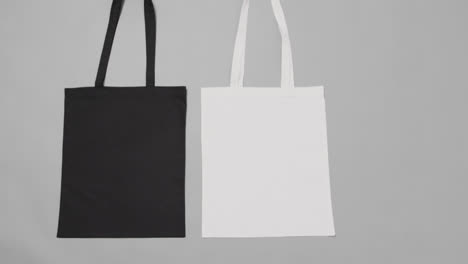 Close-up-of-white-and-black-bags-on-grey-background,-with-copy-space,-slow-motion