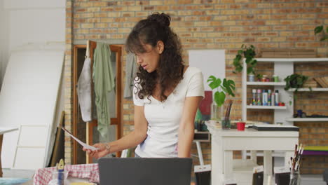 Biracial-woman-stands-in-a-creative-home-office