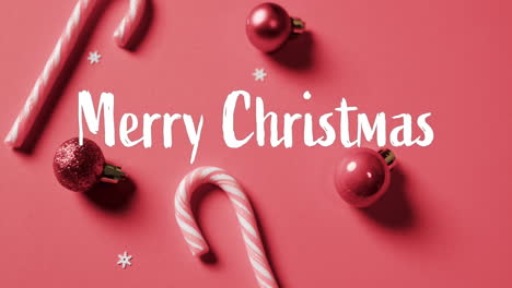 Merry-christmas-text-over-candy-canes-and-red-baubles-on-red-background