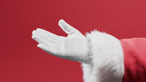 Video-of-hand-of-santa-claus-in-white-glove-with-copy-space-on-red-background