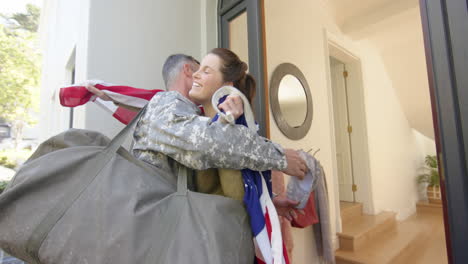 Happy-caucasian-woman-with-flag-welcoming-home-male-soldier