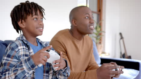 Glücklicher-Afroamerikanischer-Vater-Und-Sohn,-Die-Videospiele-Spielen-Und-Zu-Hause-Herumalbern,-Zeitlupe