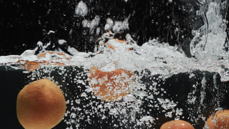 Video-Von-Orangen,-Die-Ins-Wasser-Fallen,-Mit-Kopierraum-Auf-Schwarzem-Hintergrund
