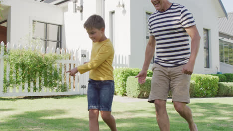 Happy-caucasian-grandfather-and-grandson-playing-football-in-garden,-slow-motion
