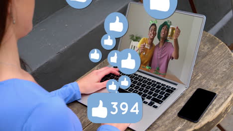 Animation-of-like-icons-with-increasing-numbers-over-rear-view-of-woman-having-video-call-on-laptop