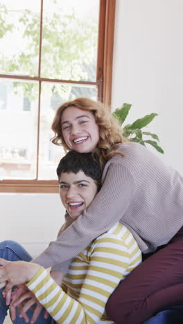 Glückliches-Kaukasisches-Lesbisches-Paar-Sitzt,-Umarmt-Und-Lächelt-Im-Sonnigen-Wohnzimmer
