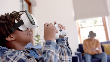 African-american-father-and-son-playing-video-game-using-vr-headsets-at-home,-slow-motion