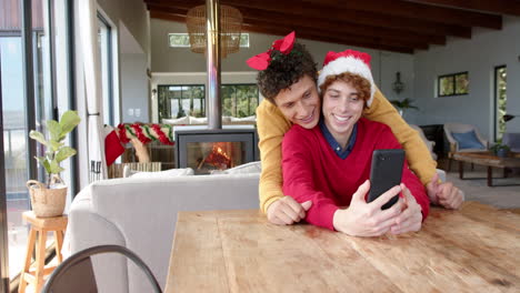 Diverse-gay-male-couple-using-smartphone-for-video-call-at-home,-slow-motion,-copy-space