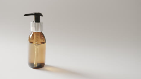 Close-up-of-glass-bottle-with-pump-with-copy-space-on-white-background