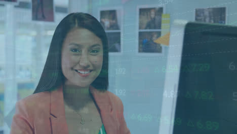 Animation-of-stock-market-data-processing-against-asian-woman-using-laptop-and-smiling-at-office