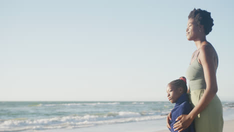 Happy-african-american-mother-and-daughter-embracing-at-beach,-in-slow-motion,-with-copy-space