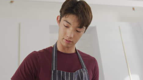 Asian-boy-wearing-apron-preparing-food-in-the-kitchen-at-home