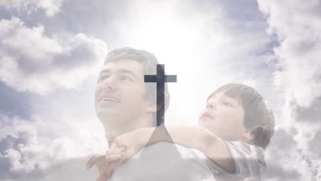 Animation-of-crucifix-cross-monument-and-cloudy-sky-over-caucasian-father-carrying-son