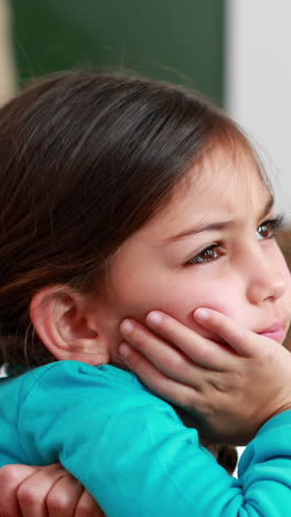 Vertical-video-of-a-biracial-girl-daydreaming-at-school,-with-copy-space