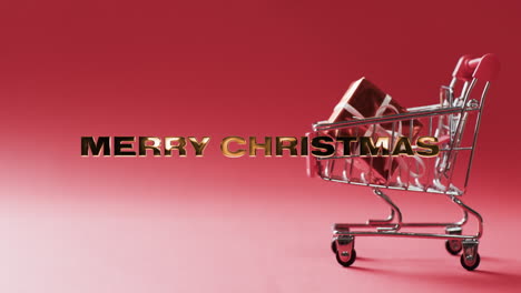 Merru-shristmas-text-in-gold-over-gifts-in-shopping-cart-on-red-background