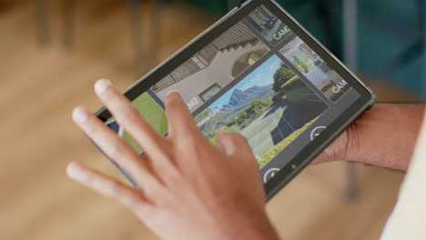 Hands-of-biracial-man-using-tablet-with-home-security-camera-views-on-screen,-slow-motion