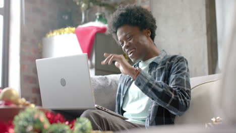 Glücklicher-Afroamerikanischer-Mann,-Der-Zu-Hause-Mit-Einem-Laptop-Auf-Dem-Sofa-Sitzt-Und-Videoanrufe-In-Zeitlupe-Macht