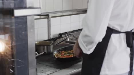 Caucasianale-chef-frying-vegetables-in-fry-in-kitchen,-slow-motion