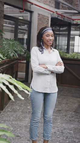 Vertical-video-portrait-of-happy-african-american-casual-businesswoman-smiling-in-office