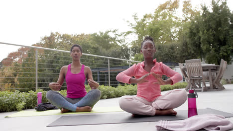 Glückliche-Afroamerikanische-Tochter-Und-Mutter-Praktizieren-Yoga-Im-Sonnigen-Garten,-Zeitlupe
