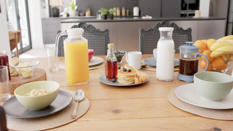 Close-up-of-table-with-breakfast-food-and-drinks-in-kitchen,-slow-motion