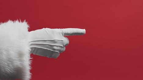 Video-of-hand-of-santa-claus-in-white-glove-pointing-with-copy-space-on-red-background