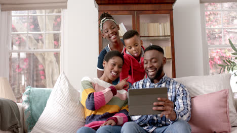 Happy-african-american-parents,-son-and-daughter-sitting-and-using-tablet-at-home,-slow-motion