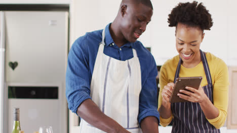 Video-of-happy-african-american-couple-cooking-together-with-tablet